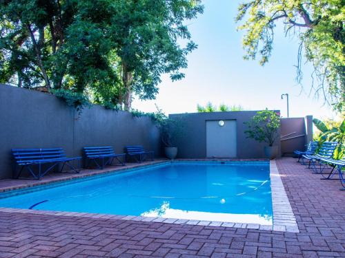 Una piscina con sillas azules y una valla. en Riverview Guesthouse, en Upington