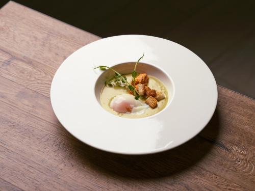 a white plate with a bowl of food on a table at Garrigae Domaine de l'Esterel - piscine & SPA Cinq Mondes in Saint-Raphaël