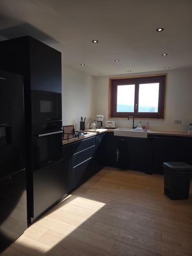 Una cocina con gabinetes negros y un fregadero y una ventana. en Catalunya, en Font-Romeu-Odeillo-Via