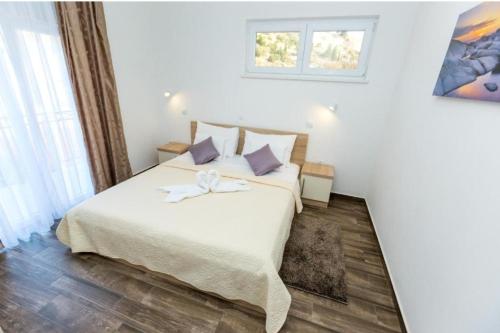 a bedroom with a large white bed with purple pillows at Apartments & Rooms Jure in Viniština