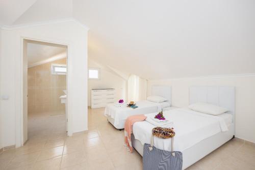 Un dormitorio blanco con dos camas y un espejo. en Golden Heights 15, en Ölüdeniz