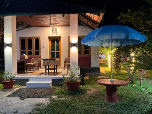 a house with a table and an umbrella in the yard at Lake Homes in Varkala