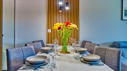 a dining table with a vase of flowers on it at Apartamenty z basenem i saunami STONE HILL RESORT II VIP Centrum by Royal Aparts in Szklarska Poręba