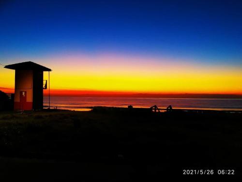 a group of people walking on the beach at sunset at Casa com Jacuzzi em Itapoa, 400m da Praia Aceita Pets in Itapoa