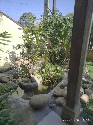 a garden with a fountain and trees and rocks at Casa com Jacuzzi em Itapoa, 400m da Praia Aceita Pets in Itapoa