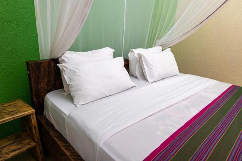 a bedroom with a bed with white sheets and pillows at Kabalega Resort - Hoima in Hoima