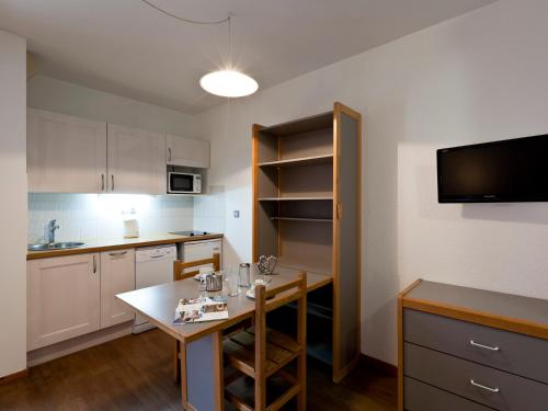 Il comprend une cuisine avec une table et une télévision murale. dans l'établissement Studio 2 pers, centre-ville, près des thermes, balcon, WiFi, télécabine à 200m, parking dispo - FR-1-512-97, à Brides-les-Bains