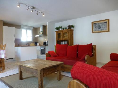 un salon avec un canapé rouge et une table dans l'établissement Charmant T3 à Brides-les-Bains - Résidence Moderne Proche Télécabine et Thermes - FR-1-512-148, à Brides-les-Bains