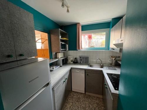 - une cuisine avec des murs bleus, des placards blancs et un évier dans l'établissement Charmant T2 au Centre de Brides-les-Bains avec Balcon, Parking et WIFI - FR-1-512-194, à Brides-les-Bains