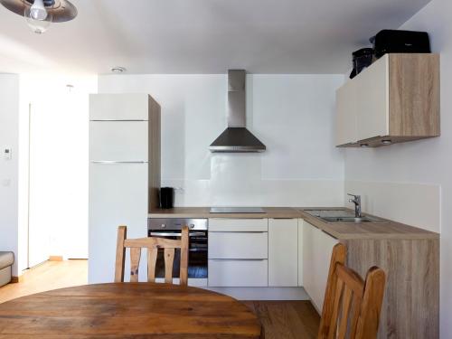 une cuisine avec des armoires blanches et une table en bois dans l'établissement Appartement neuf 2* au centre de Brides avec terrasse, proche télécabines et commerces - FR-1-512-41, à Brides-les-Bains