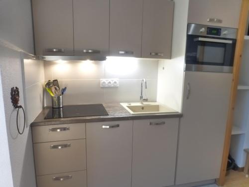 une petite cuisine avec des armoires blanches et un évier dans l'établissement Studio cosy avec balcon, Wi-Fi, proche thermes et télécabine à Brides-les-Bains - FR-1-512-51, à Brides-les-Bains