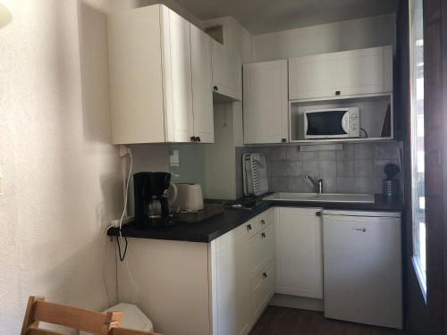 une petite cuisine avec des armoires blanches et un micro-ondes dans l'établissement Studio avec Balcon, WIFI et Parking - 4 pers, Proche Thermes, Brides-les-Bains - FR-1-512-164, à Brides-les-Bains