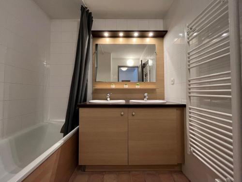 une salle de bain avec un lavabo, une baignoire et un miroir dans l'établissement Appartement spacieux 8 pers avec balcon, parking et WiFi, proche centre et thermes - FR-1-512-214, à Brides-les-Bains