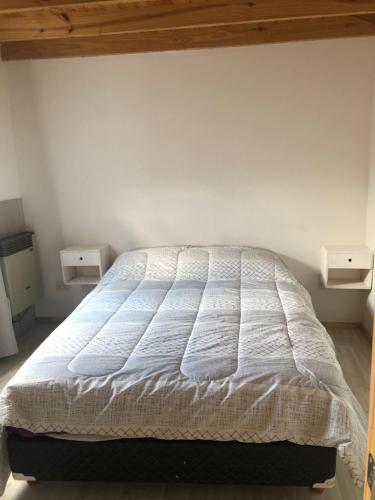 ein Schlafzimmer mit einem weißen Bett und zwei Nachttischen in der Unterkunft Casita San Martín in San Martín de los Andes
