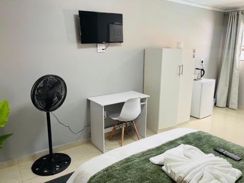 a bedroom with a bed and a desk and a fan at Maita Guest in Cape Town