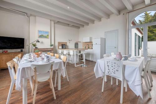une salle à manger avec des tables et des chaises blanches dans l'établissement Face Mer - Plage Villa familiale pour 12, à Saint-Michel-Chef-Chef