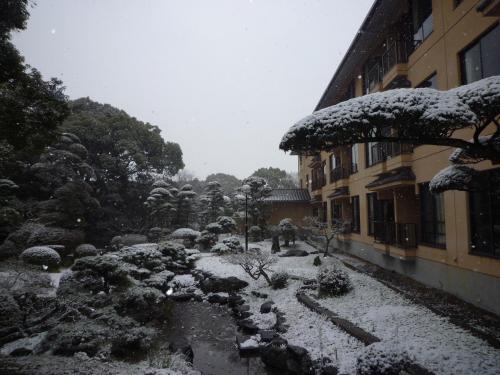a garden covered in snow next to a building at Yanagawa Hakuryuso in Yanagawa