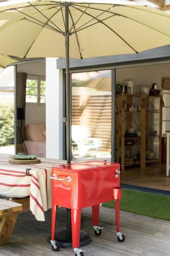 a red table with an umbrella on a deck at Gde Villa Familiale - Hossegor in Soorts-Hossegor