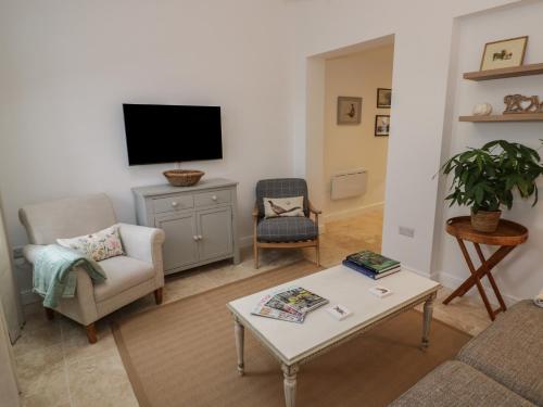 Una sala de estar con un sofá y un televisor. en Plum Barn, en Daventry