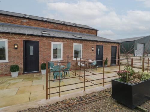 a patio with chairs and tables on a brick building at Pear Barn in Daventry