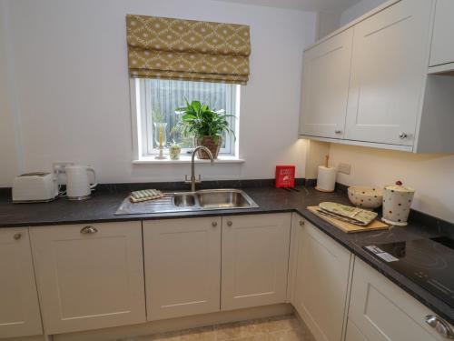 a kitchen with white cabinets and a sink and a window at Pear Barn in Daventry