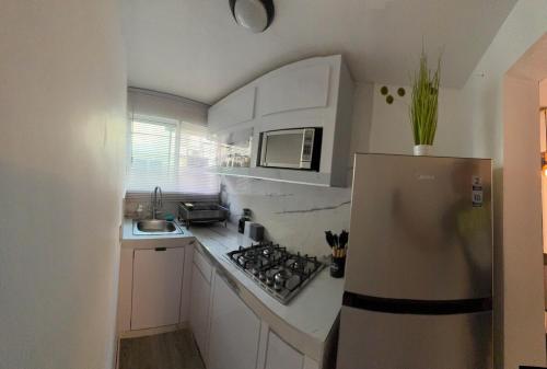 a small kitchen with white cabinets and a refrigerator at Excelente departamento en jardín Balbuena in Mexico City