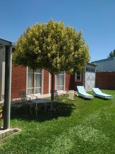 un gruppo di sedie e un albero in un cortile di Mic-Bau a Villa Elisa