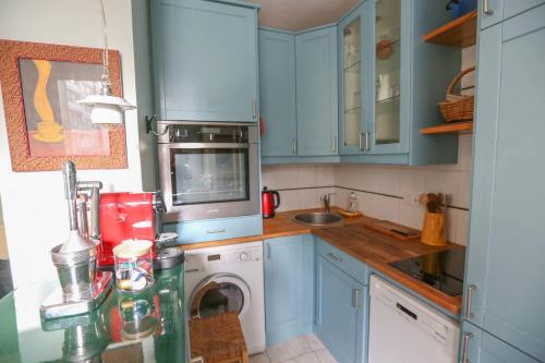 une cuisine avec des armoires bleues et une machine à laver dans l'établissement Bright pied-à-terre Eiffel Tower 4 people, à Paris