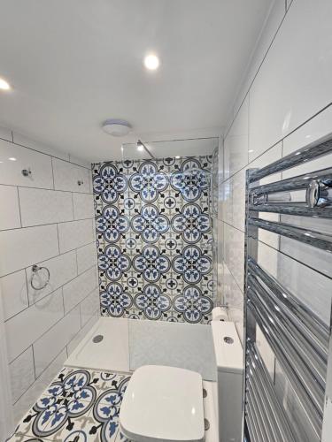 a bathroom with a toilet and a tile wall at St George's Guest House in York