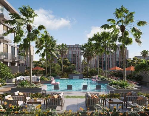 an outdoor pool with chairs and palm trees and buildings at Boutique Loft, Stylish, Cozy and Luxurious style apartment in wonderful building with 2 Pools & Gym in Dubai