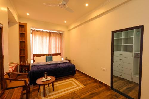 a bedroom with a bed and a table and a chair at Vista Valley Stay, Luxury 3 BHK Villa Kangra, Dharamshala in Dharamshala