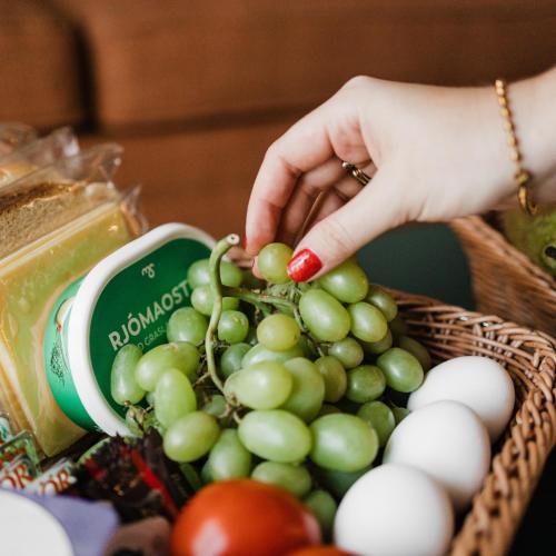 a woman picking up a bunch of green and white grapes at Reykjavik Residence Apartment Hotel in Reykjavík