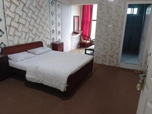 a bedroom with a bed and a room with a window at Kashmir Continental Hotel Murree in Murree
