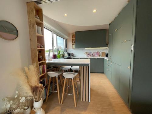 une cuisine avec des placards verts et des tabourets de bar dans l'établissement Appartement le Banville - lumineux proche hopital, à Moulins