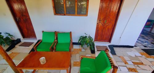 two green chairs and a table in a room at Zanz 14 Beach Bungalow in Nungwi