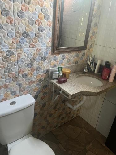 a bathroom with a toilet and a sink and a mirror at Chalé Encantos do Una in Morros