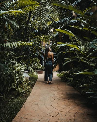 a woman walking down a path in a garden at Hotel Ciudad Vieja in Guatemala