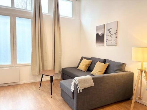 un salon avec un canapé et deux fenêtres dans l'établissement Lovely apartment - 4 guests Roubaix, à Roubaix