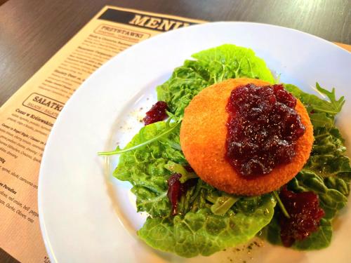 a white plate with a salad with jam on it at Hotel Dworski Galaktyczny Park in Szczecin