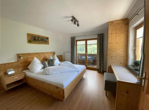 a bedroom with a bed with white sheets and a window at Kössler, Appartementhaus in Bad Hofgastein