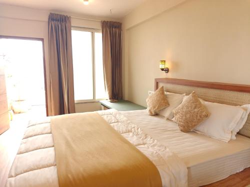 a bedroom with a large bed with white sheets and pillows at Achalaa Resort in Kolhapur