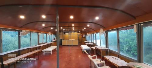 een treinwagon met banken, tafels en ramen bij Aquaholic - A Floating Villa in Jāmb