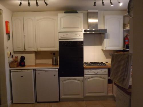 a kitchen with white cabinets and a black appliance at peaceholm at cromer in Cromer
