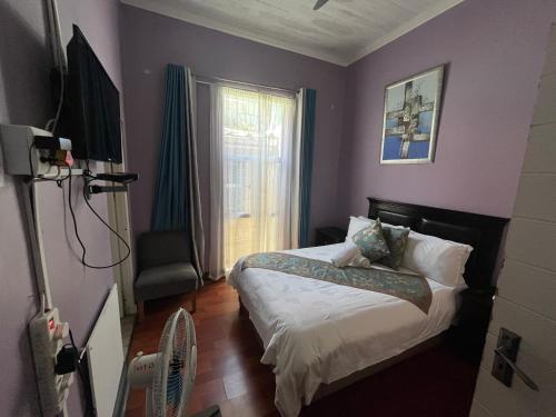 a bedroom with purple walls and a bed and a window at Zensa Hotel & Spa in East London