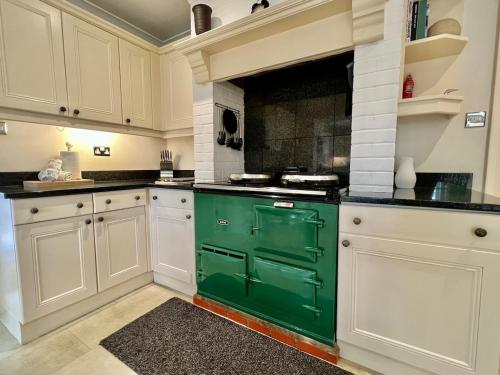 a green oven in a kitchen with white cabinets at Hedgerows House New Forest in Ringwood