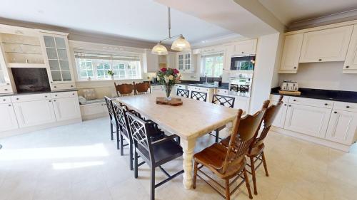 a large kitchen with a wooden table and chairs at Hedgerows House New Forest in Ringwood