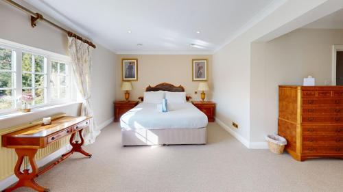 a bedroom with a bed and a desk and a window at Hedgerows House New Forest in Ringwood