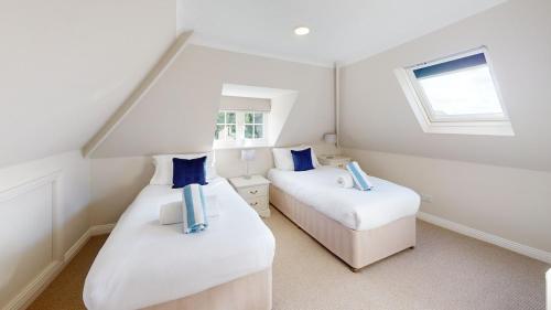 two beds in a white room with a window at Hedgerows House New Forest in Ringwood