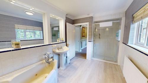 a bathroom with a tub and a sink and a shower at Hedgerows House New Forest in Ringwood