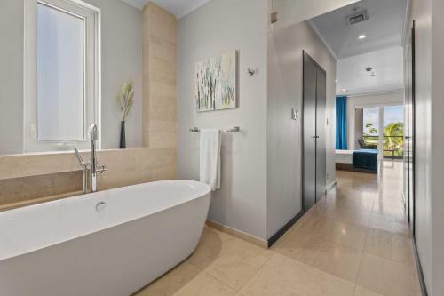 a white bathroom with a large tub and a window at Eagle Beach - Larimar Delights 3BR condo - LV201 in Palm-Eagle Beach